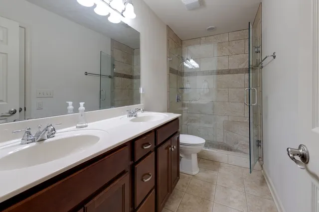 a bathroom with a double vanity sink toilet and shower