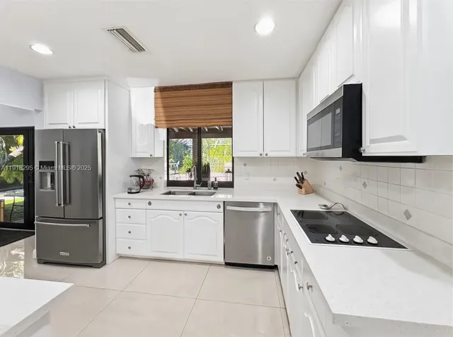 a kitchen with stainless steel appliances kitchen island granite countertop a refrigerator and a stove top oven