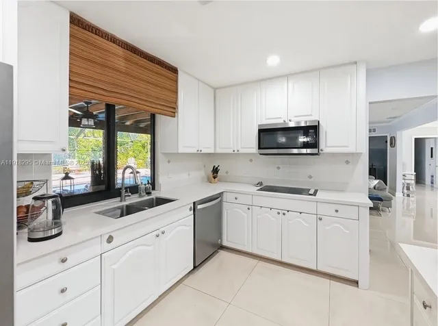 a kitchen with granite countertop a refrigerator and a stove top oven