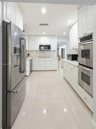 a kitchen with granite countertop a refrigerator and a stove top oven