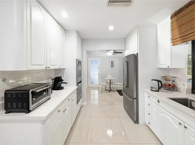 a kitchen with white cabinets and refrigerator