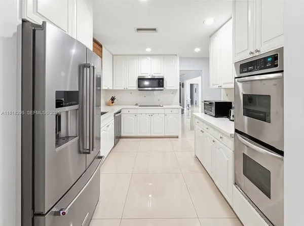 a kitchen with white cabinets and refrigerator