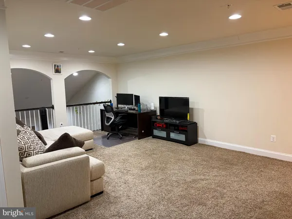 a living room with furniture a computer on a desk and a flat screen tv