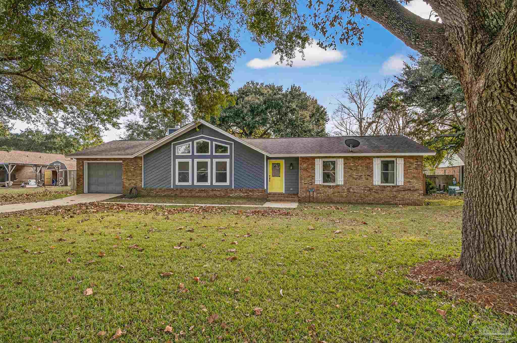a house that has a big yard with plants and large trees