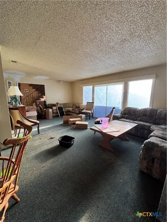 a living room with furniture kitchen view and a window