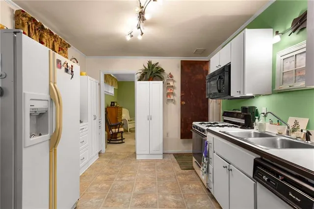 a kitchen with stainless steel appliances granite countertop a refrigerator a oven and white cabinets with wooden floor