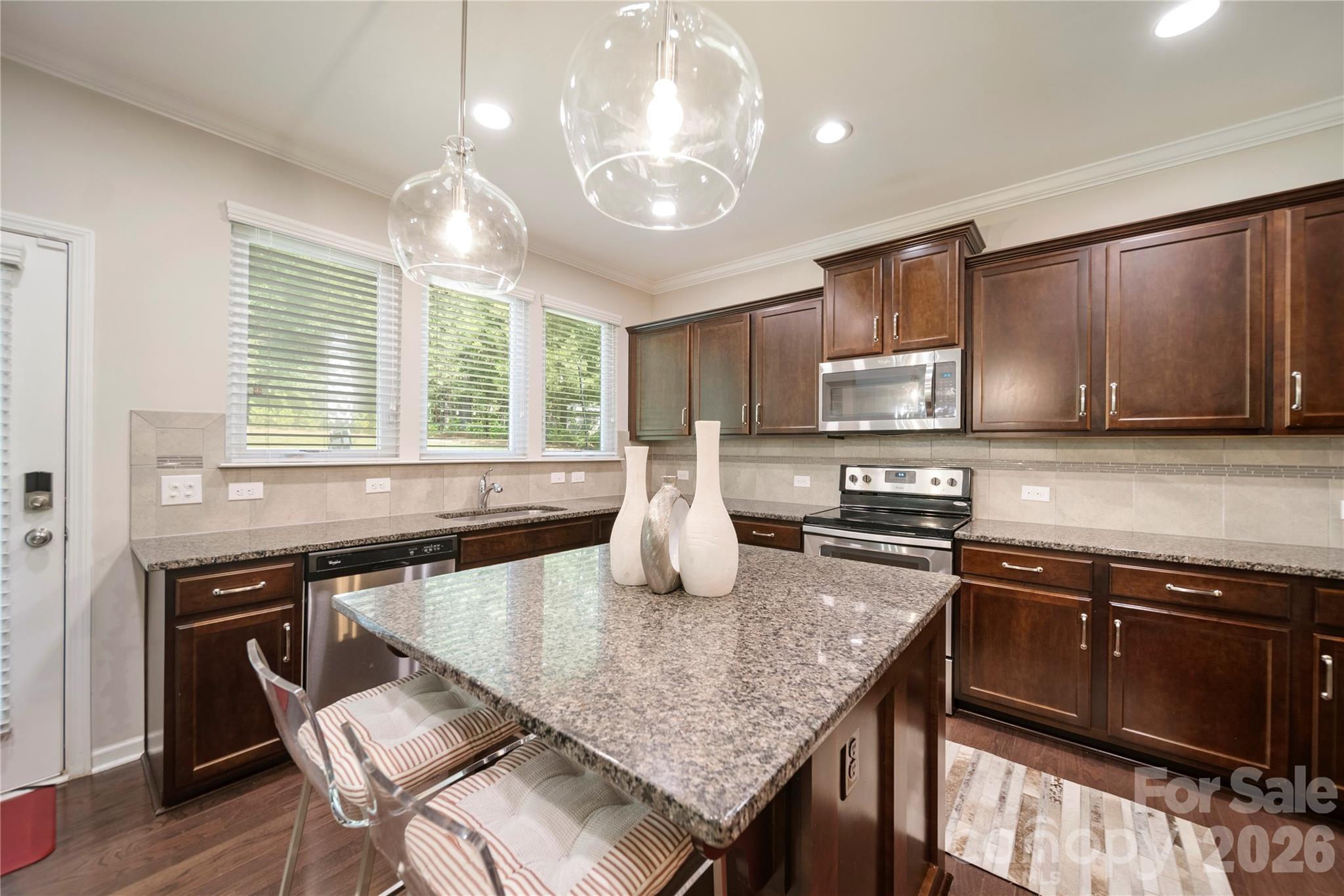8122 Mossy Rock Road Waxhaw, NC 28173 - Photo 9 of 28 a kitchen with stainless steel appliances granite countertop a stove top oven a sink dishwasher a dining table and chairs with wooden floor