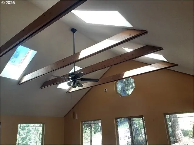 a view of an empty room with window and wooden floor