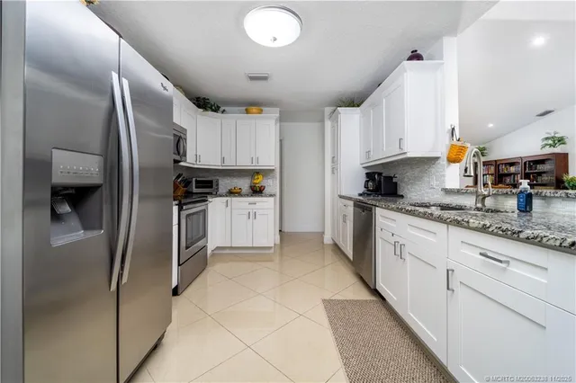 a kitchen with granite countertop a refrigerator sink and cabinets