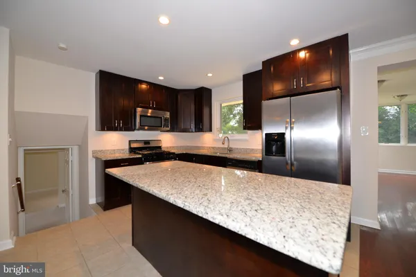 a kitchen with stainless steel appliances granite countertop a sink a refrigerator and a wooden floors