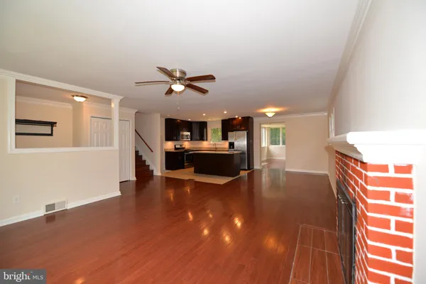 a view of an empty room with kitchen appliances and a ceiling fan