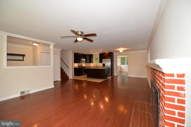 a view of an empty room with kitchen appliances and a ceiling fan