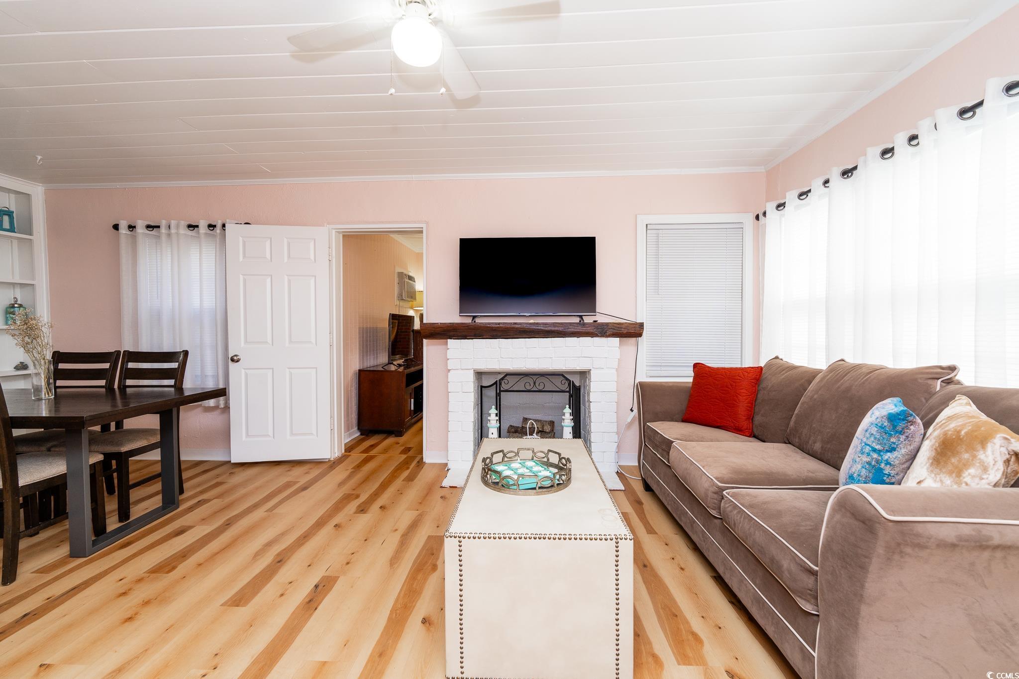 114 North Pinewood Drive Surfside Beach, SC 29575 - Photo 21 of 40 Living room with hardwood / wood-style floors, ceiling fan, crown molding, and a fireplace