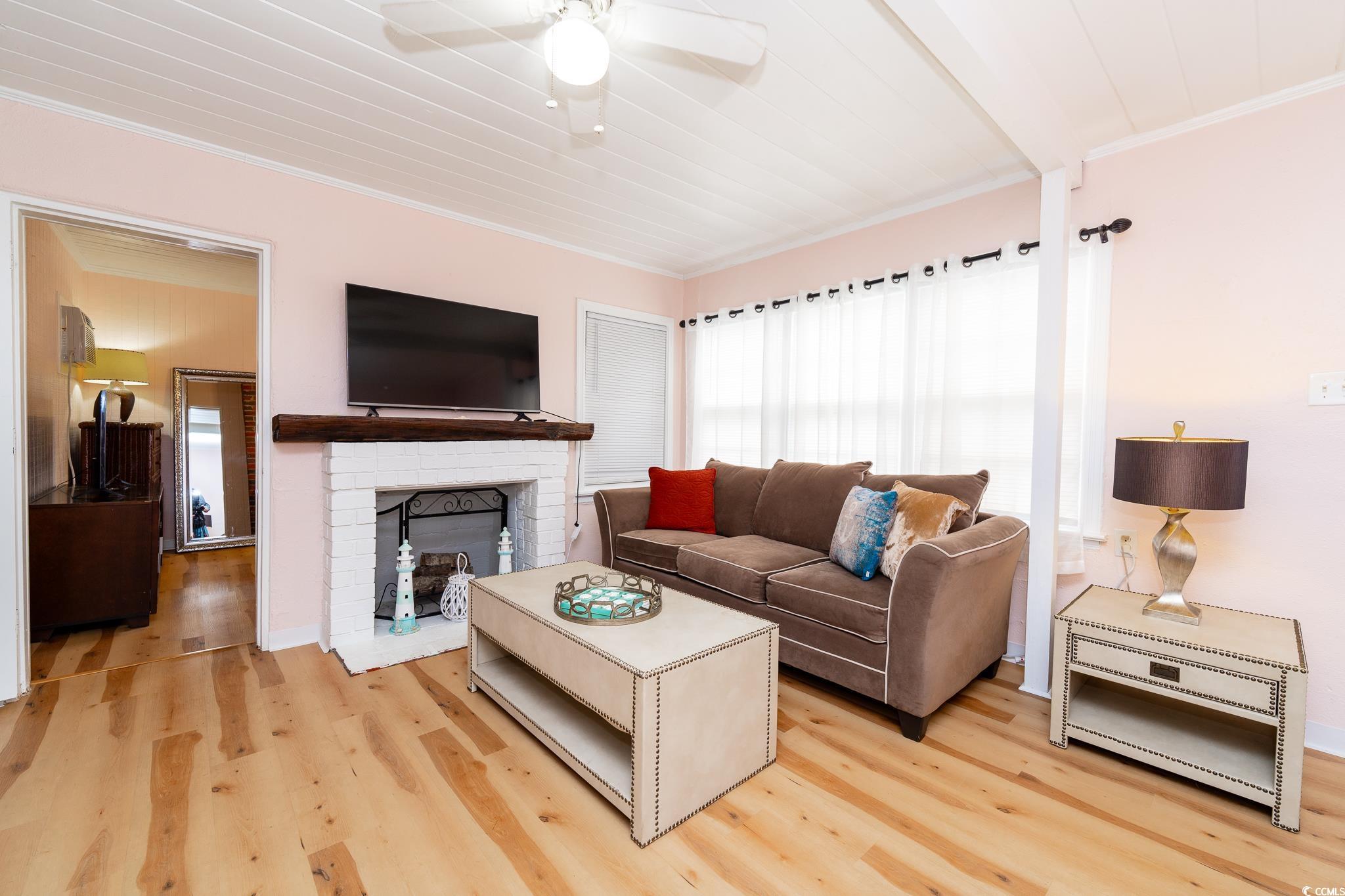 114 North Pinewood Drive Surfside Beach, SC 29575 - Photo 22 of 40 Living room with hardwood / wood-style flooring, a brick fireplace, ceiling fan, and crown molding