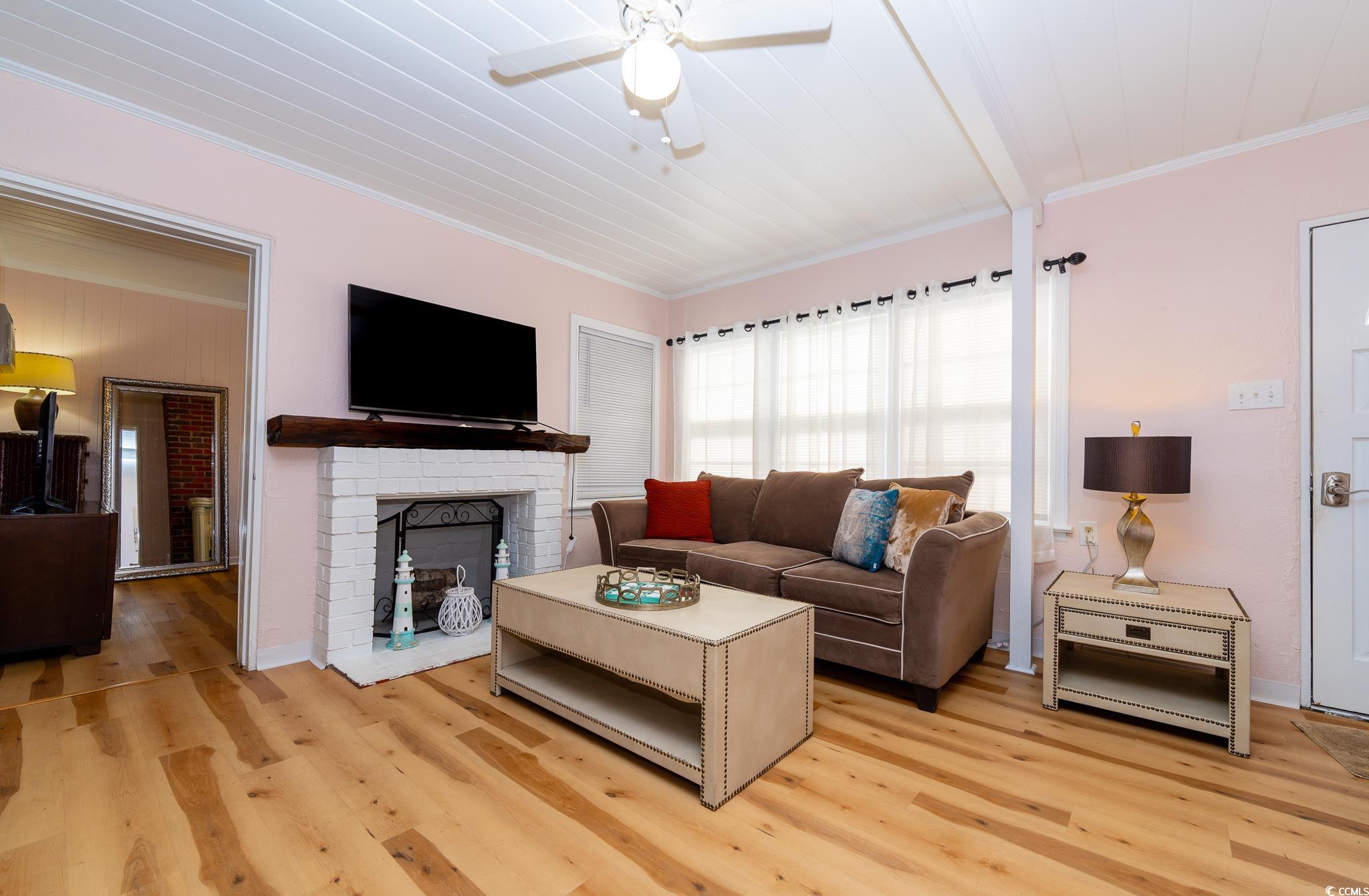 114 North Pinewood Drive Surfside Beach, SC 29575 - Photo 29 of 40 Living room featuring ceiling fan, light hardwood / wood-style floors, ornamental molding, and a fireplace