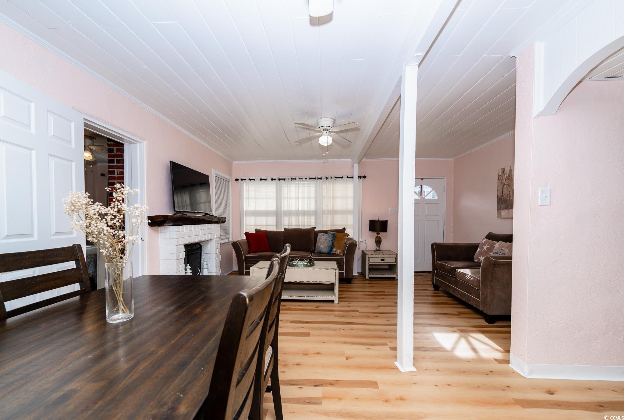 114 North Pinewood Drive Surfside Beach, SC 29575 - Photo 34 of 40 Dining space with a brick fireplace, ceiling fan, ornamental molding, and light wood-type flooring