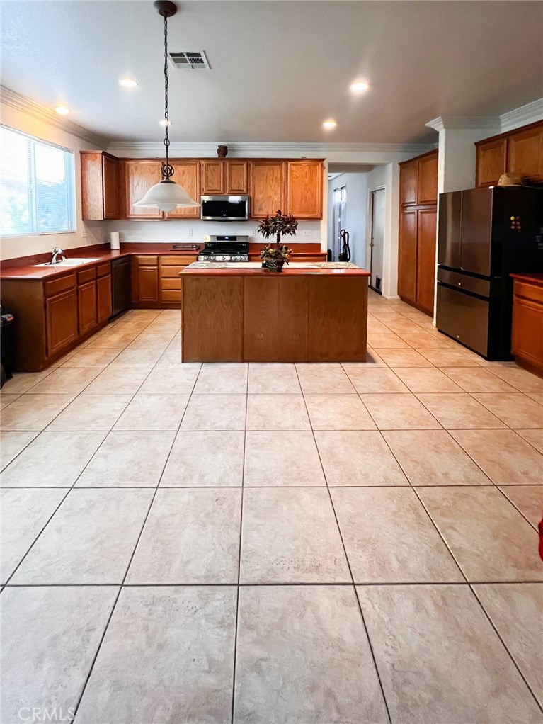3857 Bella Torre Road Perris, CA 92571 - Photo 8 of 25 a large kitchen with granite countertop a large stove a sink dishwasher and a refrigerator with wooden cabinets