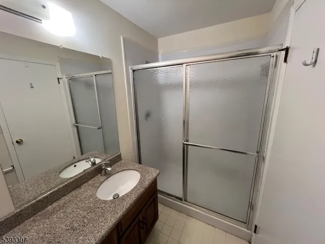 a bathroom with a granite countertop sink mirror and shower