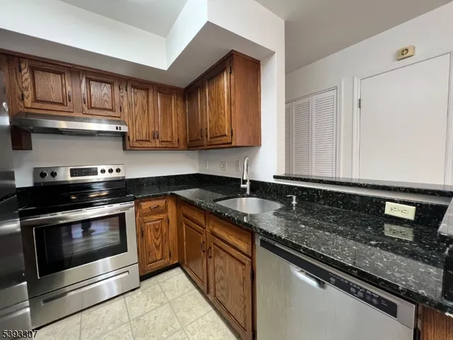 a kitchen with granite countertop stainless steel appliances a stove sink and cabinets