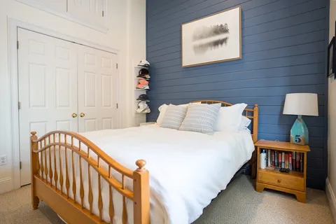 a bedroom with a bed and a lamp on dresser