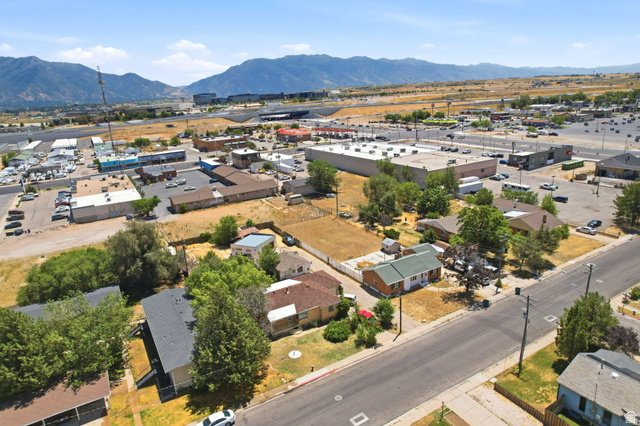 5480 South 2000th Street West Roy, UT 84067 - Photo 34 of 36 Aerial view showcasing a mix of residential and commercial properties with mountainous terrain as a distant backdrop