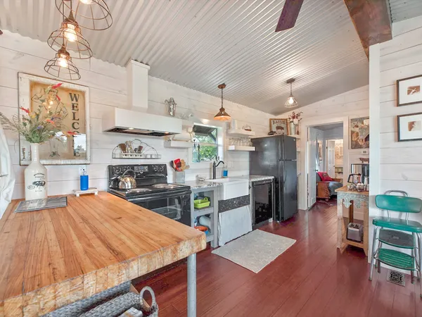 a open kitchen with stainless steel appliances kitchen island granite countertop a refrigerator oven a sink dishwasher and a stove with wooden floor