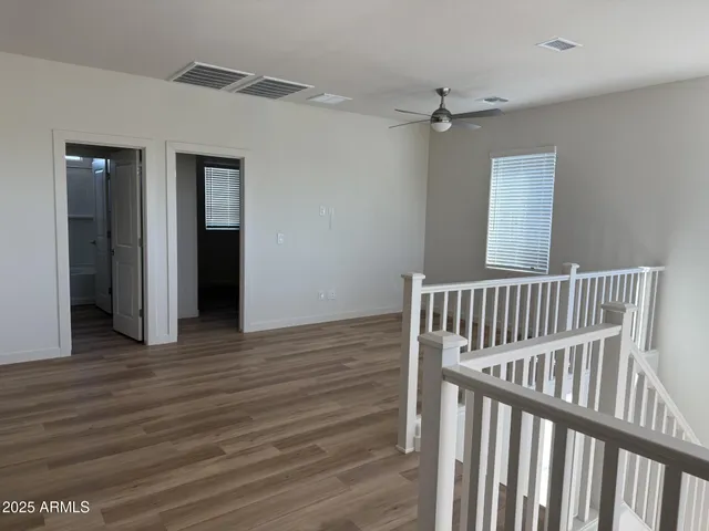 a view of a hallway with wooden floor and a ceiling fan