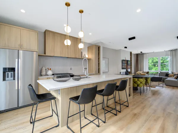 a kitchen with stainless steel appliances granite countertop a dining table chairs refrigerator and sink