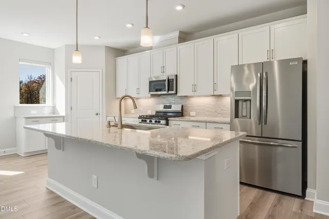 a kitchen with stainless steel appliances granite countertop a refrigerator a sink a stove and white cabinets