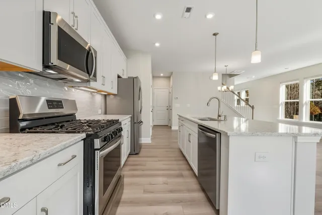 a large kitchen with stainless steel appliances granite countertop a stove a sink and a refrigerator