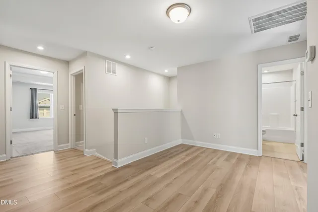 an empty room with wooden floor & windows