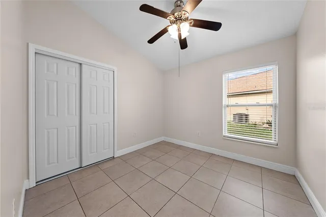 an empty room with chandelier fan and windows