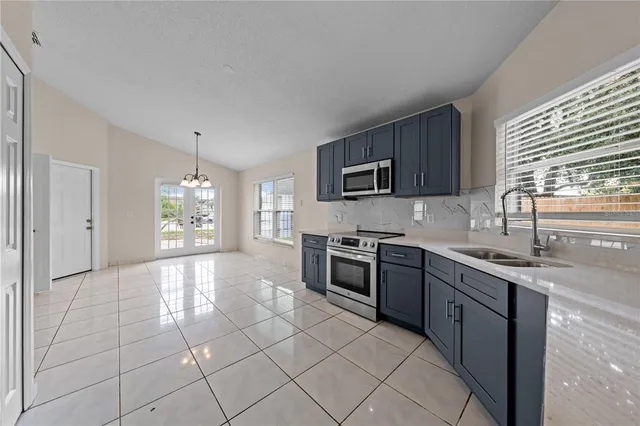 a large kitchen with stainless steel appliances granite countertop a stove top oven a sink a counter space and cabinets