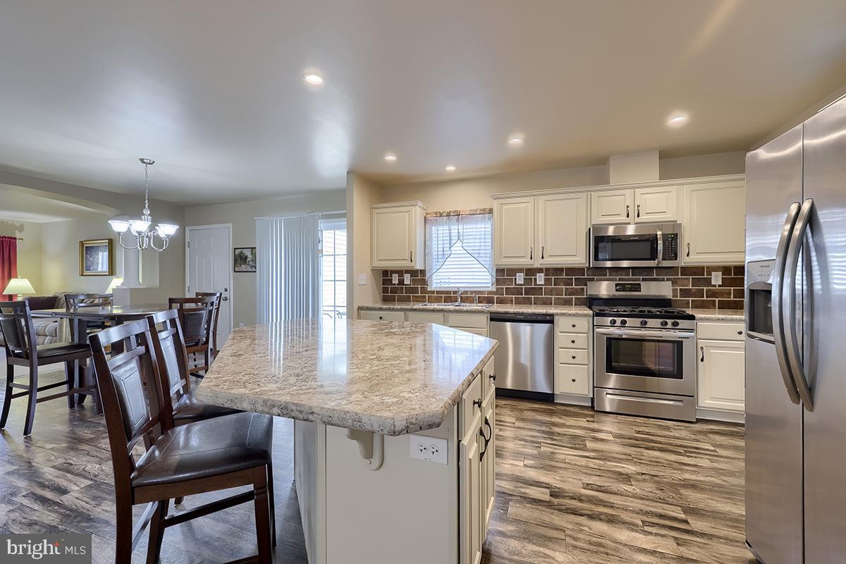 39 Westin Road Douglassville, PA 19518 - Photo 16 of 37 a kitchen with stainless steel appliances granite countertop a stove top oven a refrigerator a kitchen island and chairs with wooden floor