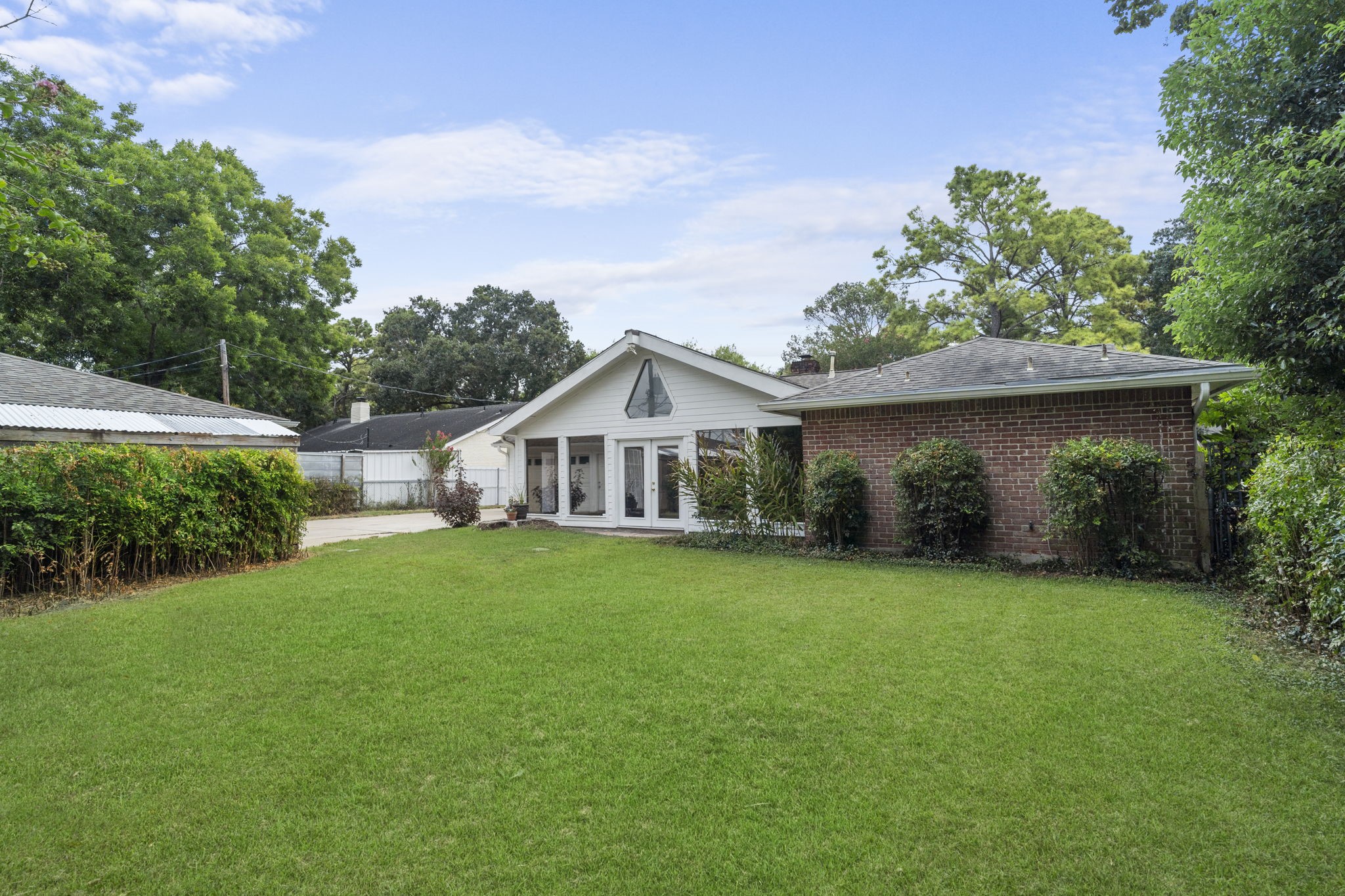 6102 Redding Road Houston, TX 77036 - Photo 35 of 40 A long, gated driveway leads to a detached 4-car garage, complemented by an adjacent greenhouse—offering exceptional space for parking, storage, hobbies, and gardening.
