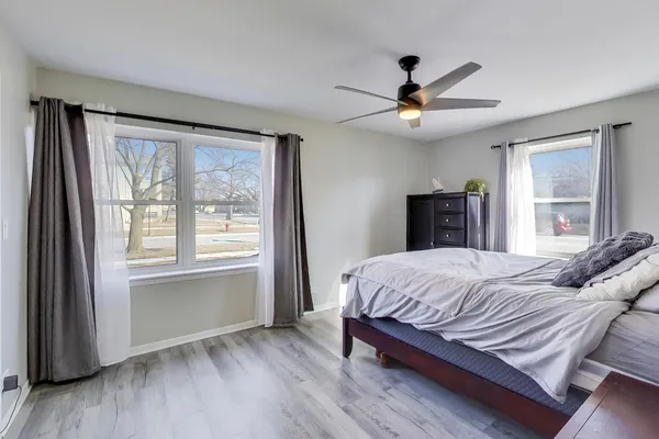 a bedroom with a large bed large window and wooden floor