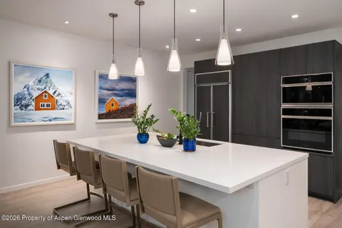a kitchen with stainless steel appliances kitchen island granite countertop a table chairs and a refrigerator
