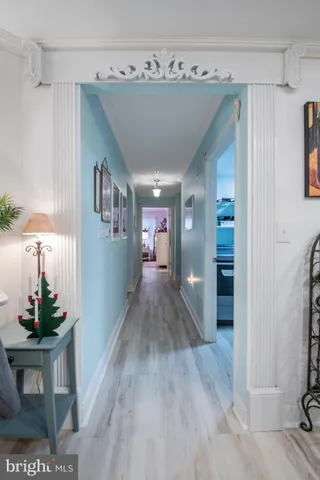 a view of a hallway to a livingroom with wooden floor and furniture