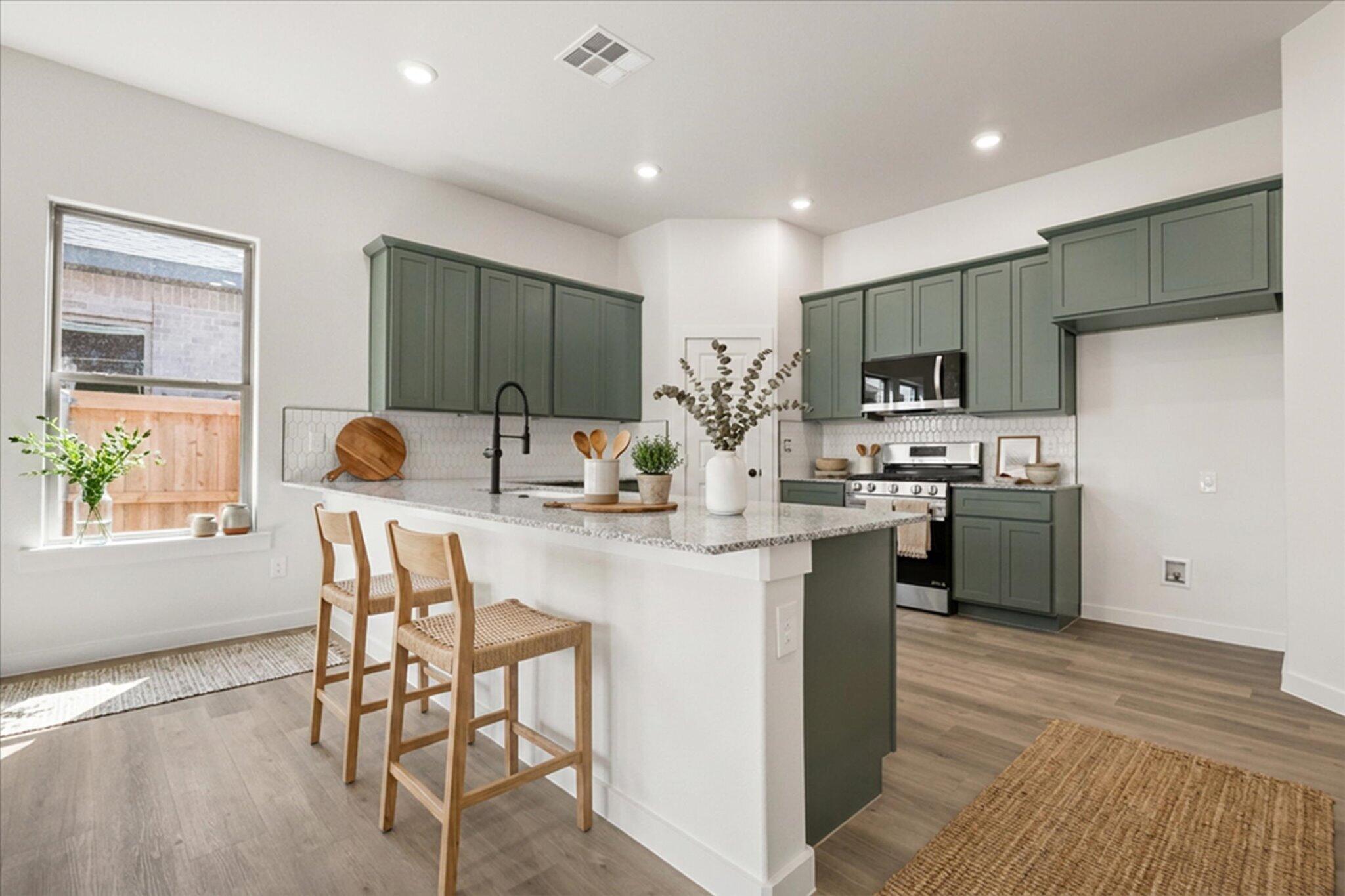 7003 53rd Street Lubbock, TX 79407 - Photo 9 of 25 a kitchen with stainless steel appliances kitchen island granite countertop a sink a stove a refrigerator cabinets and a dining table with wooden floor