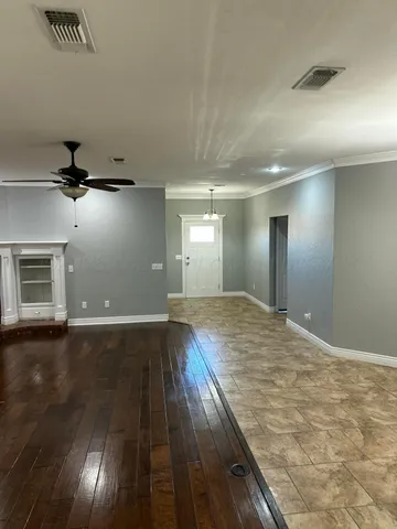 a view of an empty room with window and wooden floor
