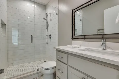 a bathroom with a granite countertop sink a toilet and a mirror
