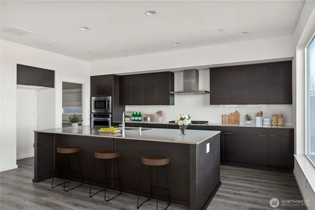 a kitchen with stainless steel appliances granite countertop a stove a sink and a microwave