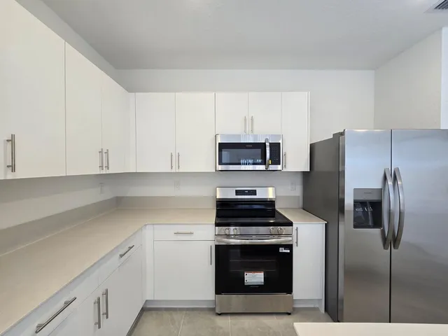 a kitchen with white cabinets and stainless steel appliances