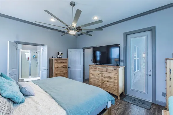 a bedroom with a bed and a flat tv screen on dresser