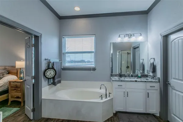 a bathroom with a tub a double vanity sink and a mirror