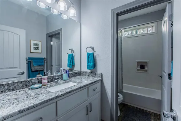 a bathroom with a granite countertop sink a toilet and a mirror