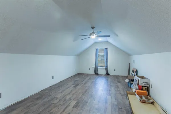 an empty room with wooden floor and fan