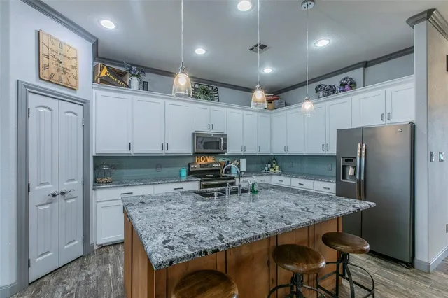 a kitchen with kitchen island a counter space refrigerator and microwave