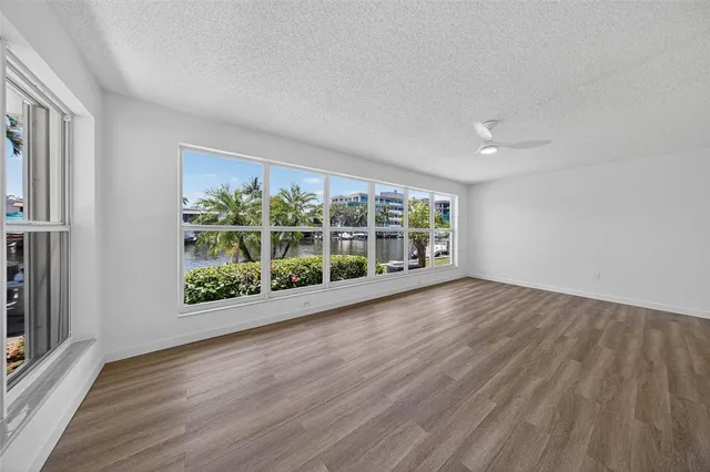 a view of empty room with wooden floor and fan