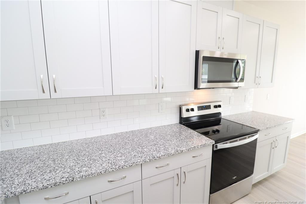 104 Kineton Woods Way Garner, NC 27529 - Photo 11 of 43 a kitchen with granite countertop white cabinets and a stove
